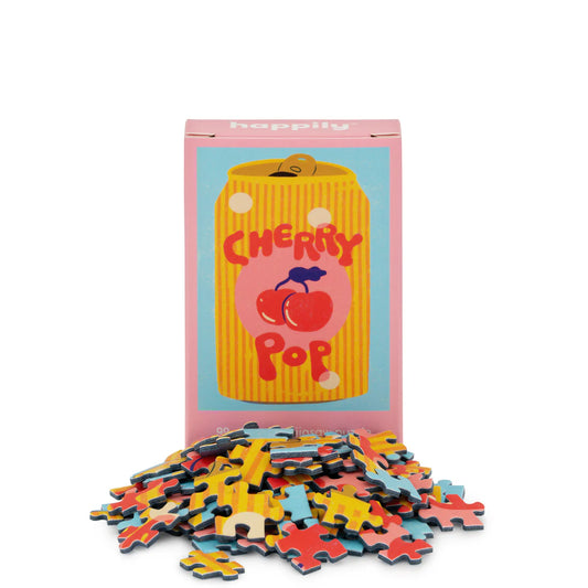 Puzzle with colourful pieces in front of a box featuring an illustration of a can of cherry pop on a white background
