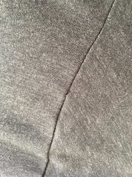 Close up of the back of the tee's left arm seam with the small hole.