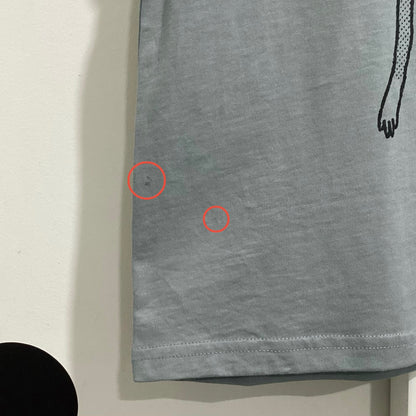 Closeup of blue-grey tee with two red circles highlighting imperfections