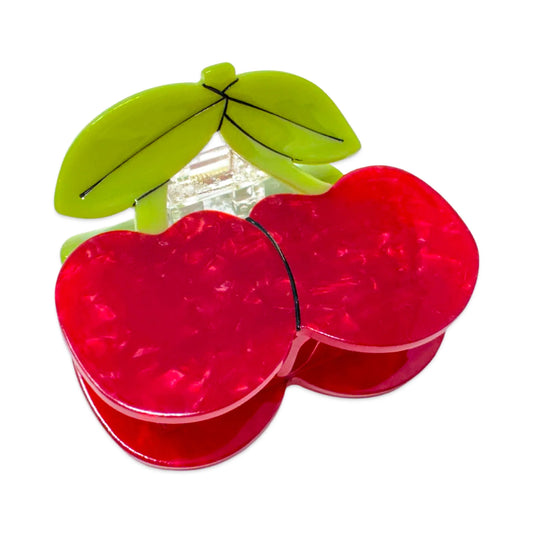 Red bio-cellulose cherries hair claw with green leaves on a white background