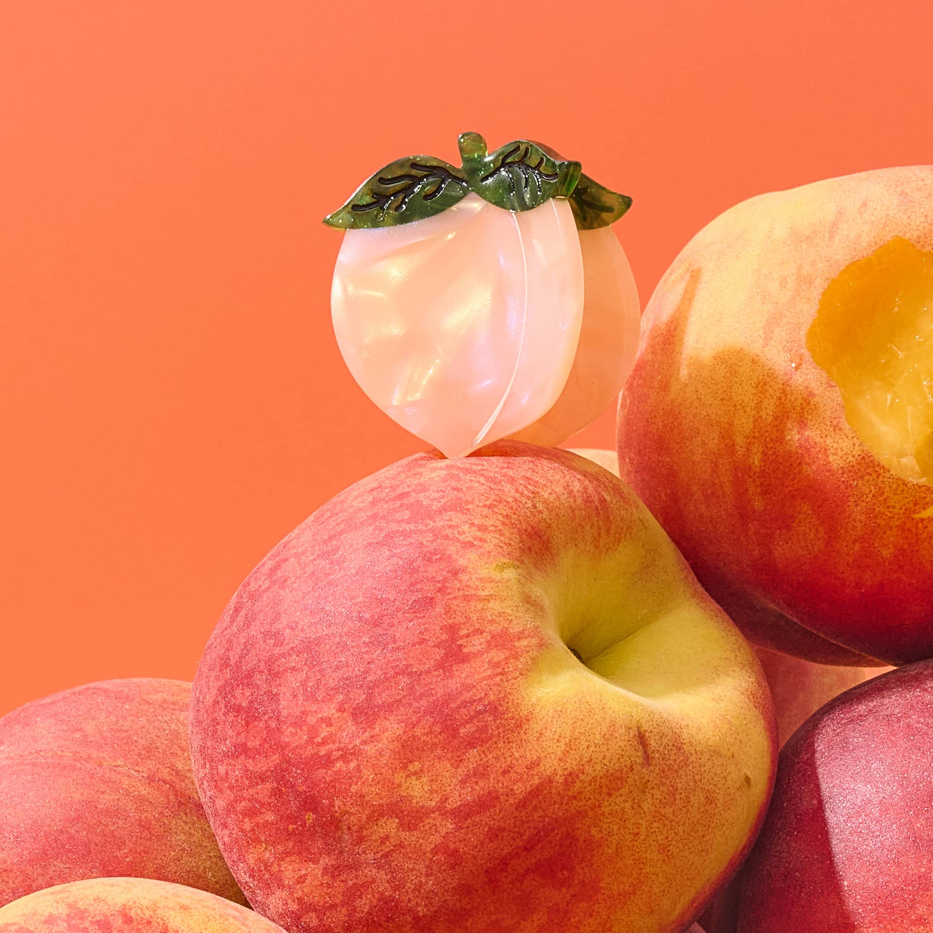 Styled view of Jenny Lemons Mini Peach Hair Claw positioned on a pile of peaches