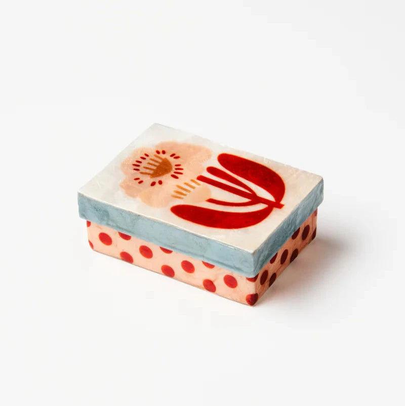 A small shell box with a flower and polka dot motif