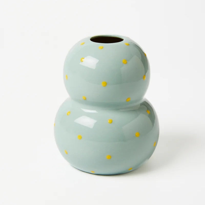 Light blue ceramic vase with yellow polka dots on a white background