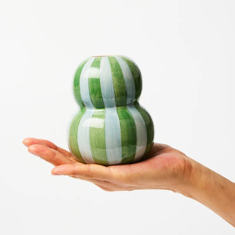 Green and white striped ceramic vase held in a hand against a white background