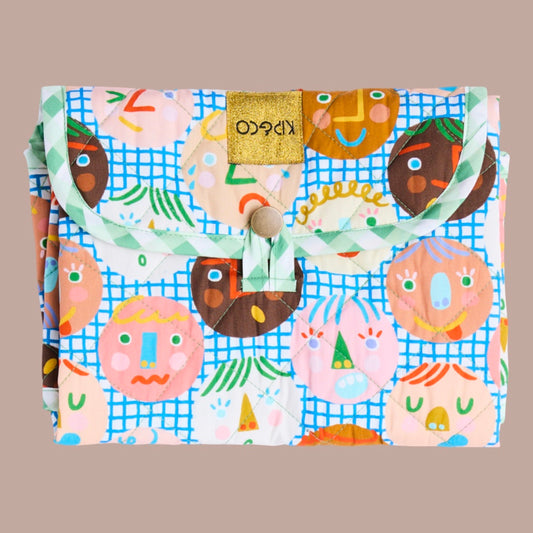 Colorful change mat folded up with cartoon face design on a beige background