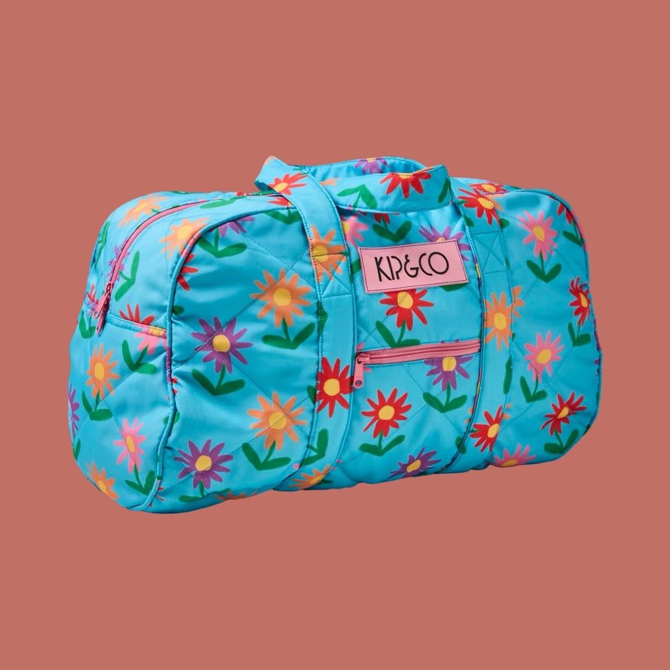 Floral-patterned duffel bag with 'KIP&CO' logo on a brown background