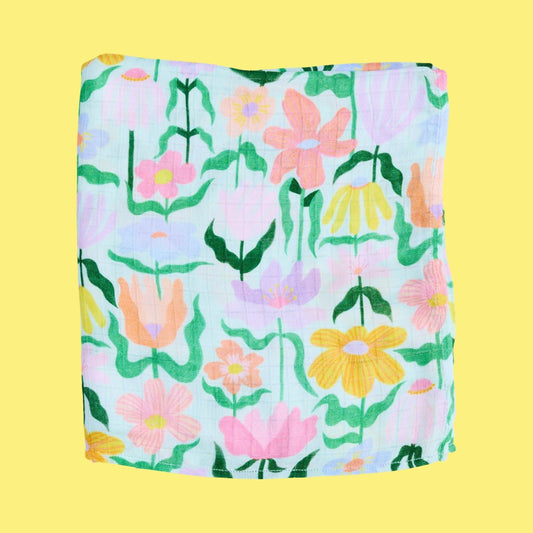 Floral patterned baby swaddle folded on a yellow background