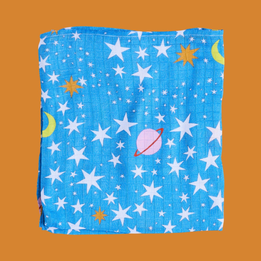 Folded baby swaddle with space-themed pattern on a brown background