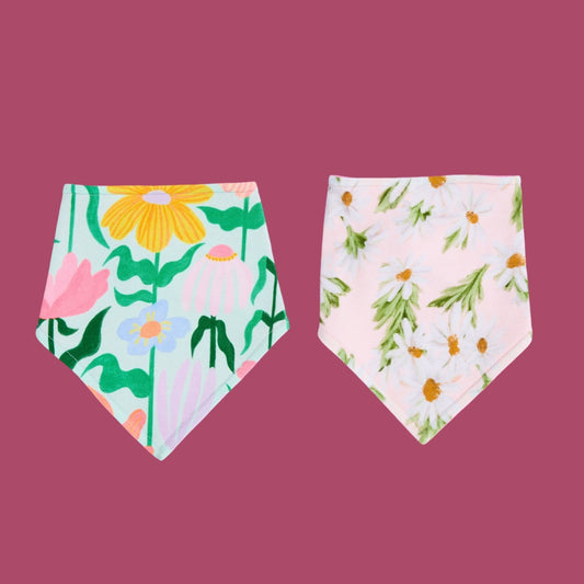 Two floral-patterned bibs on a pink background