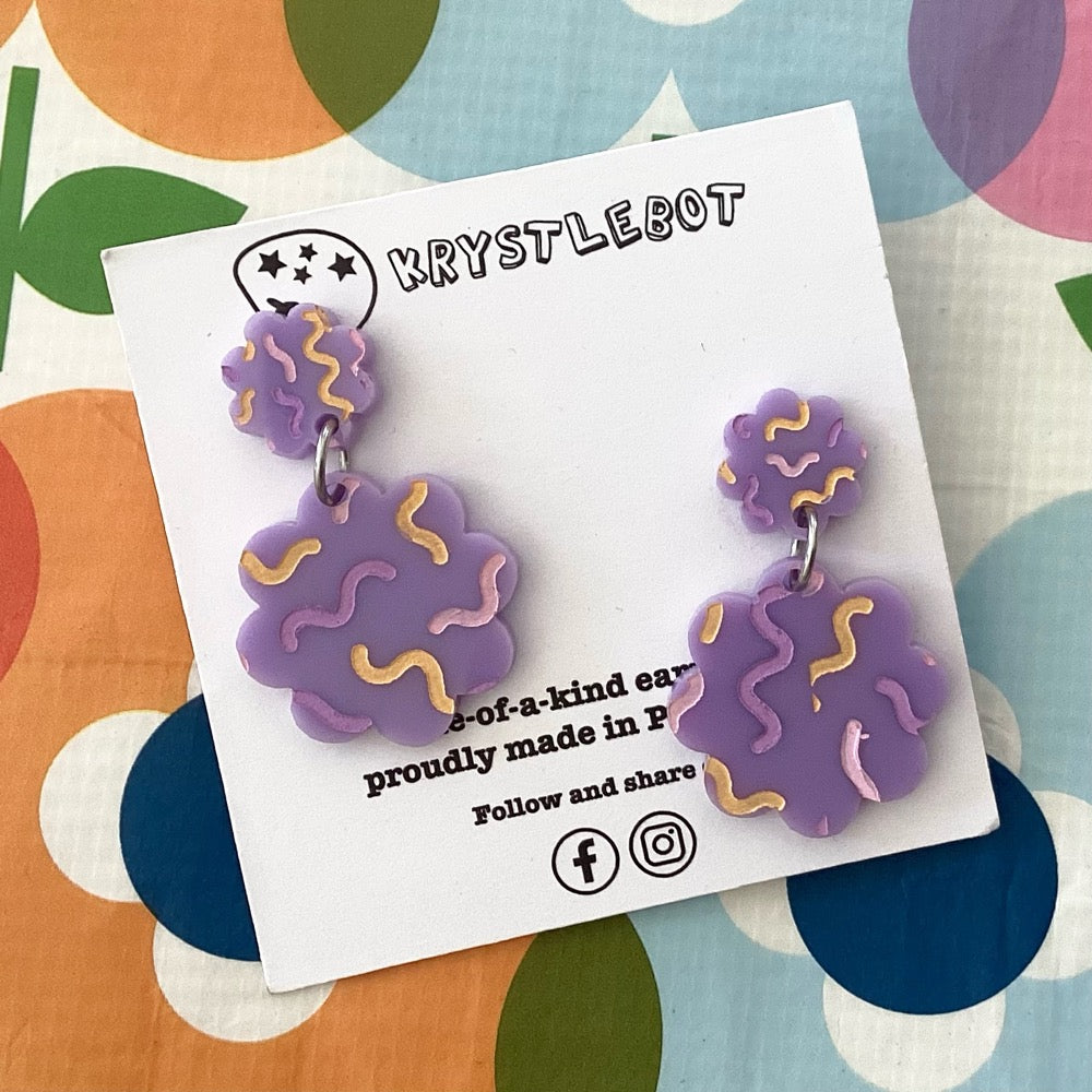 Purple earrings with multi-coloured squiggles on a Krystlebot card on a colourful background.