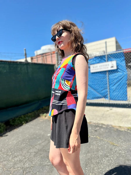 Side view of Nooworks Ansley Muscle Tee worn by model wearing sunnies and posing with hands on her sides.