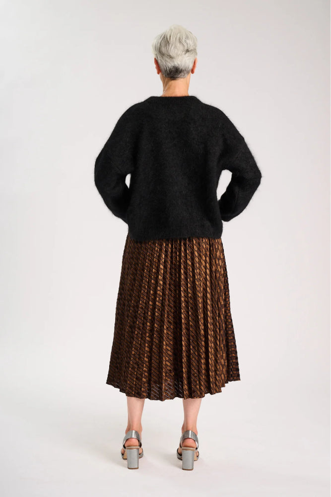 Back view of Model wearing a black sweater and pleated brown skirt on a white background