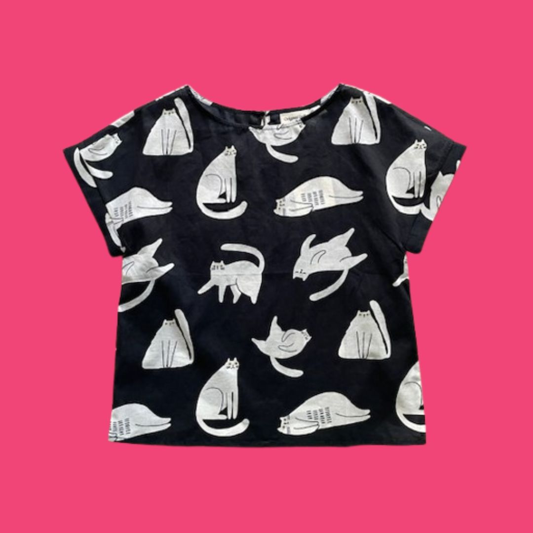 Black t-shirt with white cat pattern on a pink background