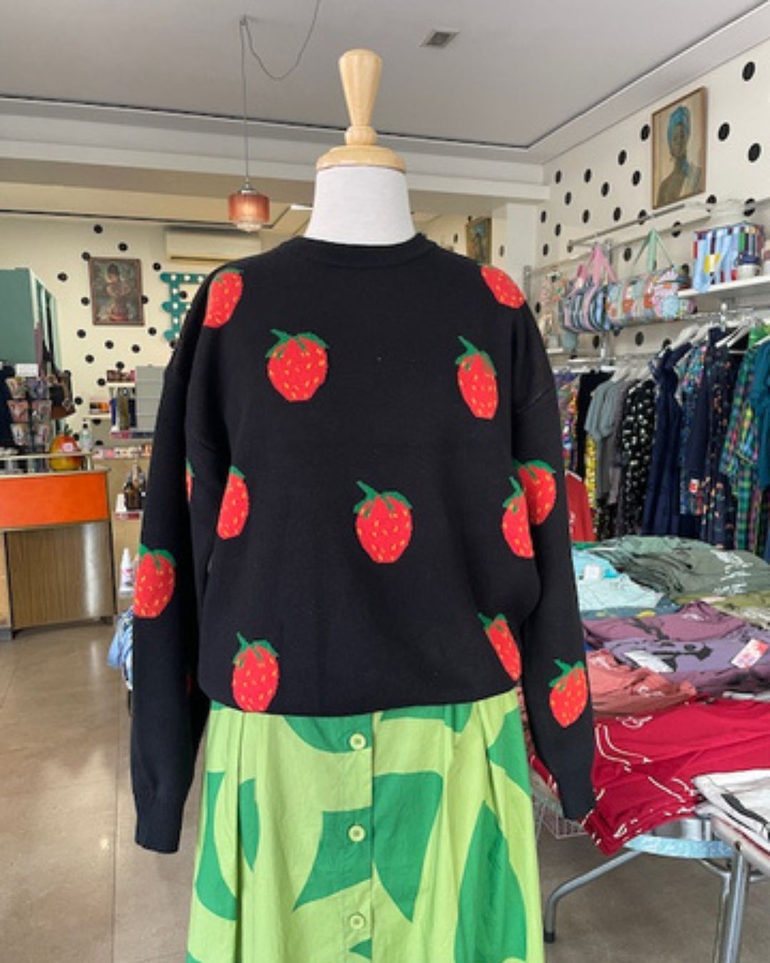 Black sweater with red strawberries patterns on Mabel our shop mannequin