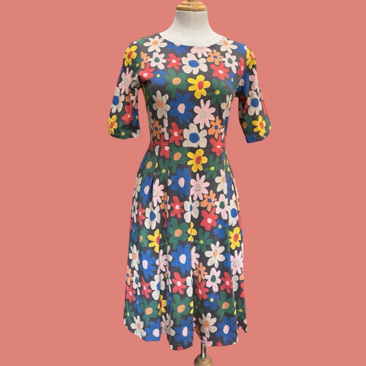 Colorful floral dress on a mannequin against a pink background