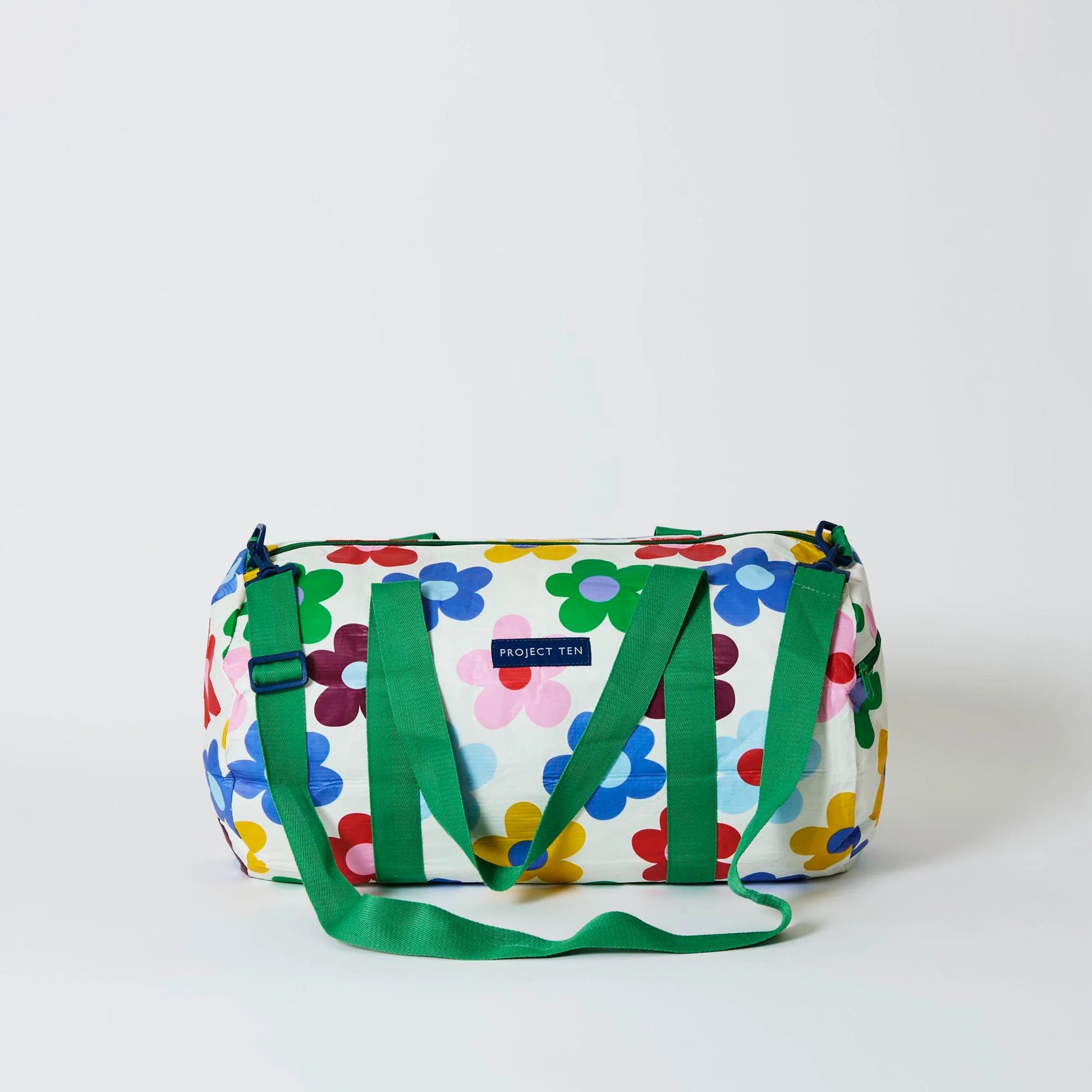 Colorful floral-patterned duffel bag with green straps on a white background