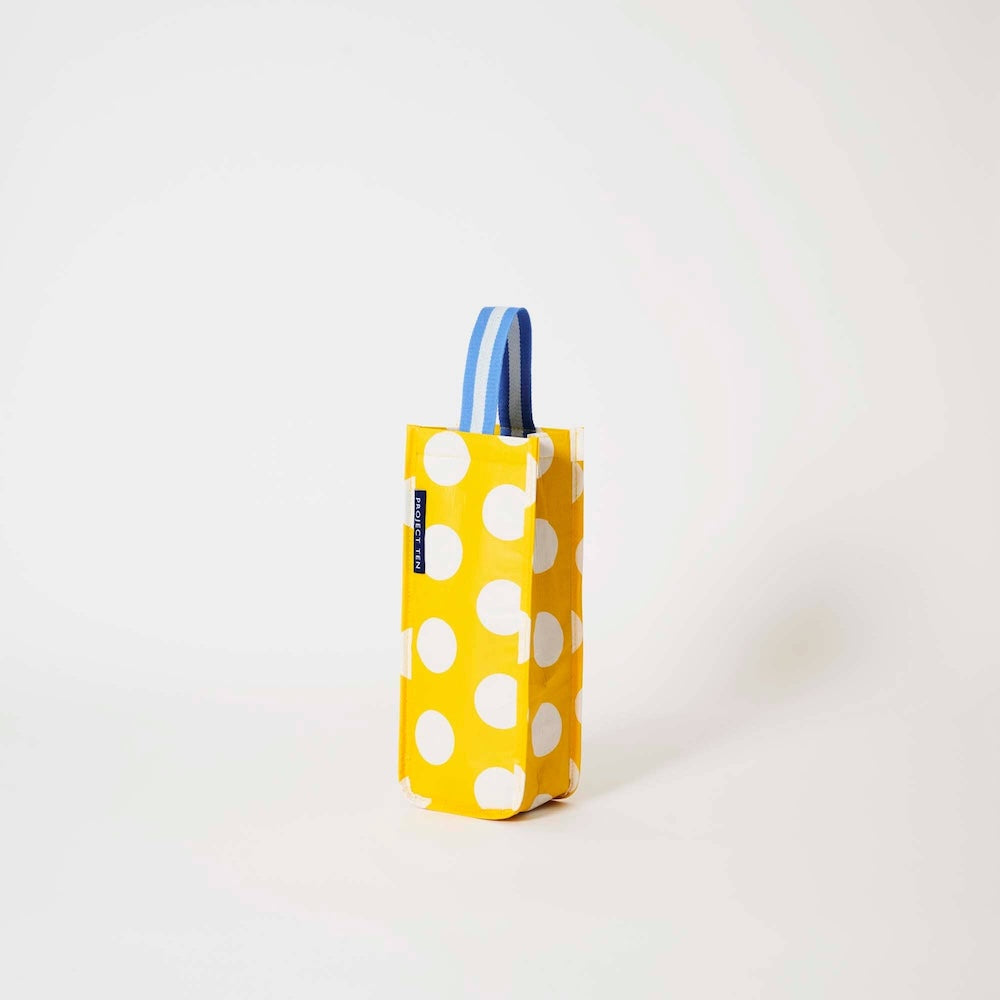 Side view of Project Ten Yellow Polka Dot Wine Bag, featuring polka dots and a blue-and-white striped handle, standing upright on a clean white background.