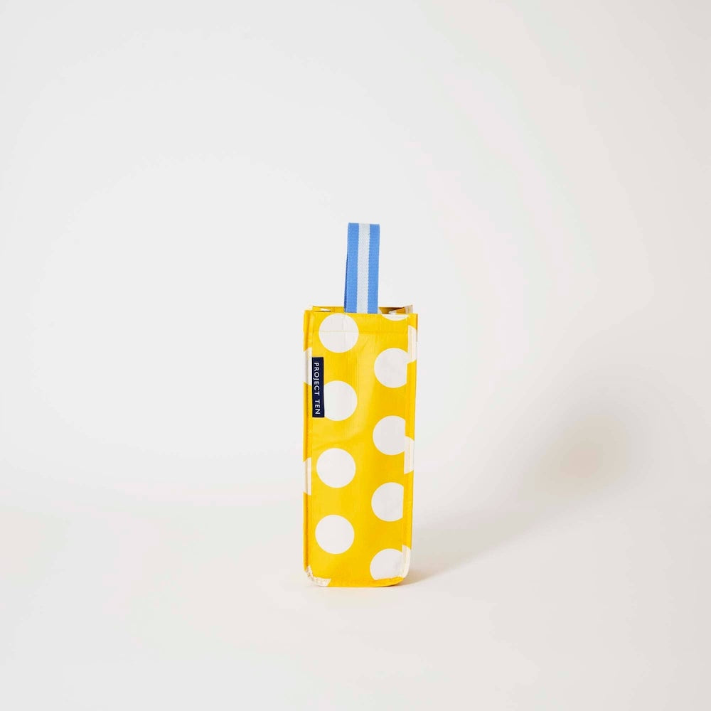 Project Ten Yellow Polka Dot Wine Bag, a yellow and white polka dot pattern bag with a blue and white striped handle, standing upright on a clean white background.