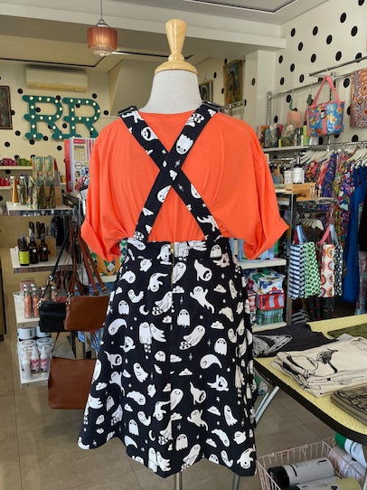 Back view of Mabel wearing an orange shirt and black and white ghost patterned pinafore in our Ruck Rover store.