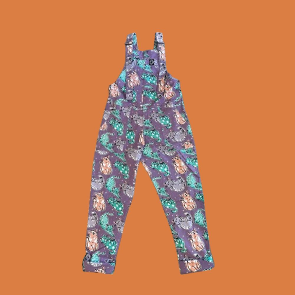 Purple overalls with cats pattern on an orange background