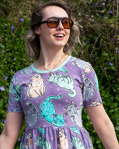 Woman wearing a purple dress with cat patterns outdoors