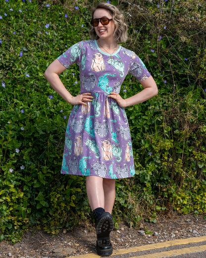 Woman wearing a car patterned dress standing outdoors with greenery in the background