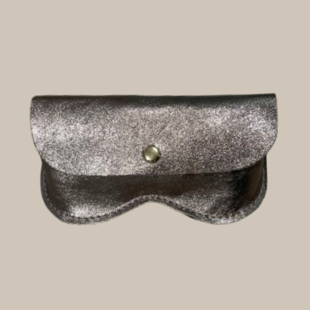 A metallic beige-taupe glasses case closure and a single round metal snap button, shown on a plain light beige background.