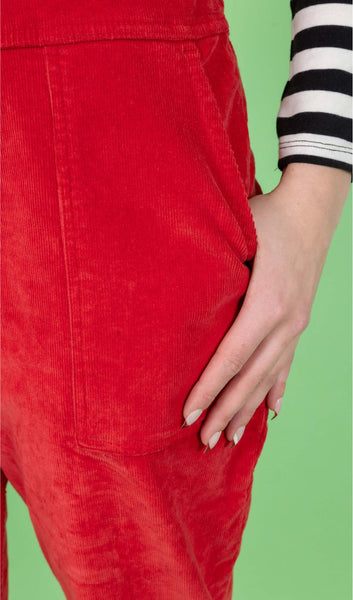 Close up of one of the side pockets of the Run & Fly Red Cord Dungarees worn by a model who has their hand partially in the pocket.