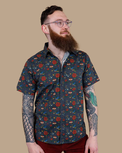 Portrait view of Model wearing Run and Fly Retro Tattoo Print Shirt and looking away from camera.