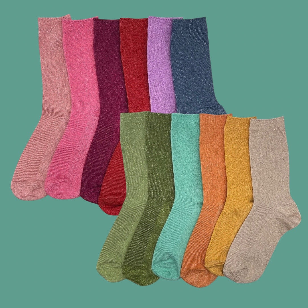 A set of ten pairs of sparkly knit crew socks in assorted colors, arranged in two overlapping rows against a turquoise background.