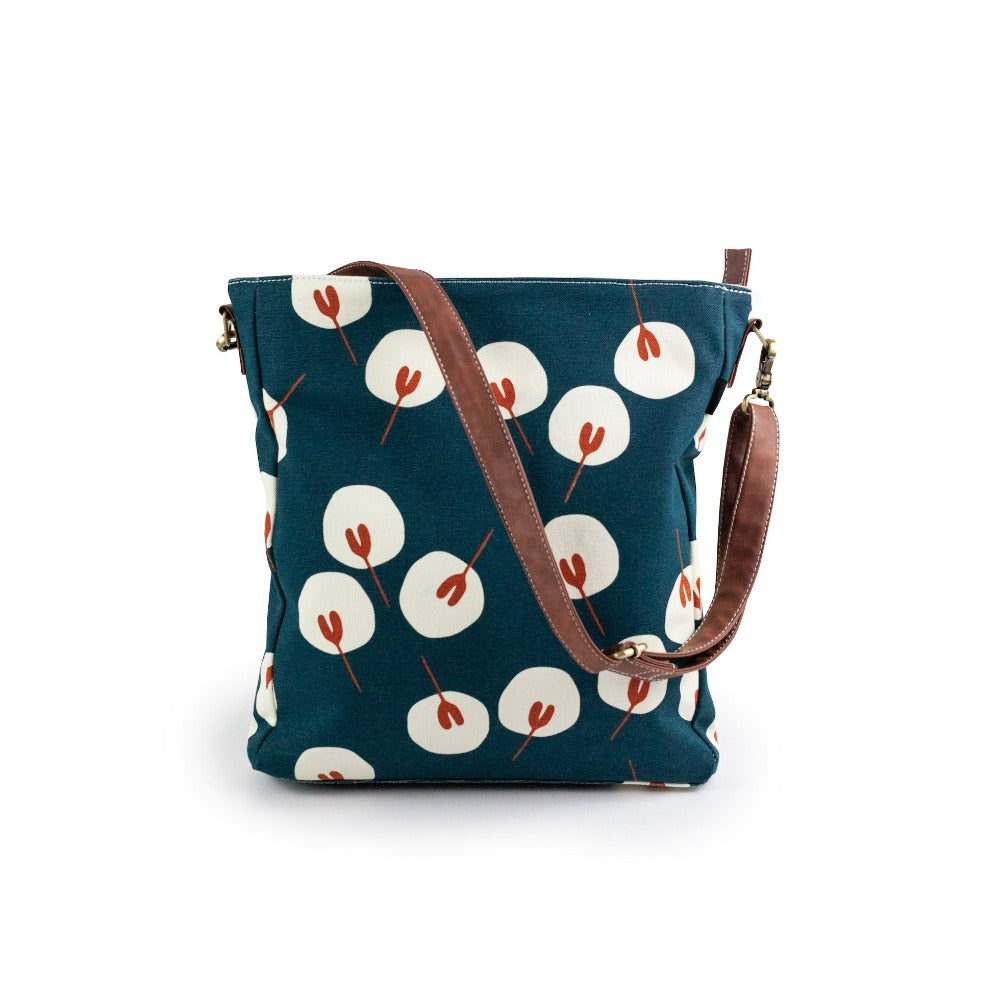 Canvas crossbody bag with a blue, red and white abstract print and brown vegan leather strap.