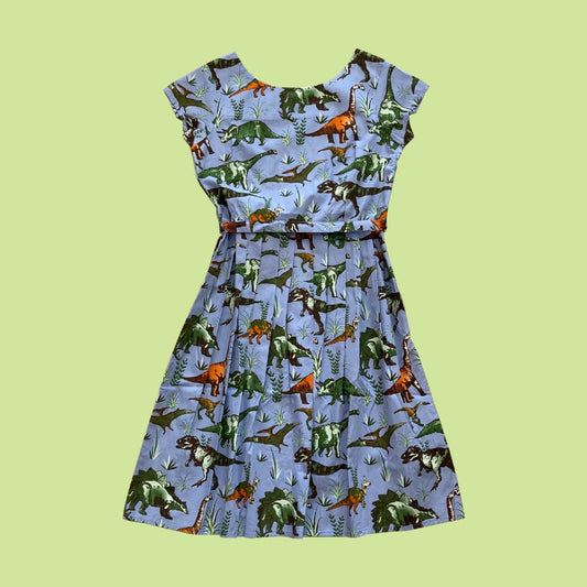 Pale blue dress with cap sleeves and a pleated skirt, covered in a dinosaur print. 